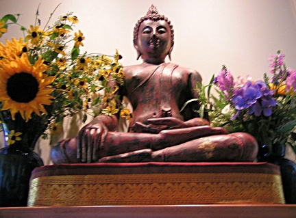 Buddha rupa adorned with summer flowers